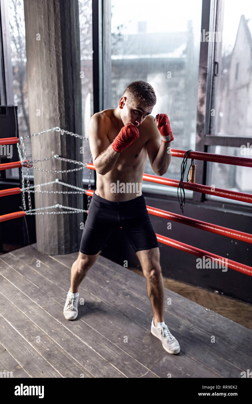 Athletic boxer uomo con bende di rosso su mani nell'anello Foto Stock