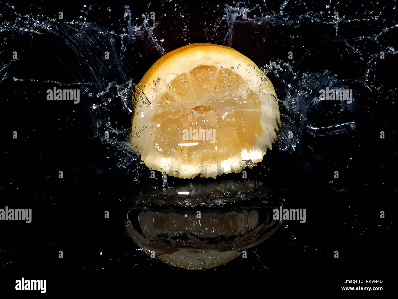 Il limone di cadere in acqua e provocando splash. Sfondo nero. Foto Stock