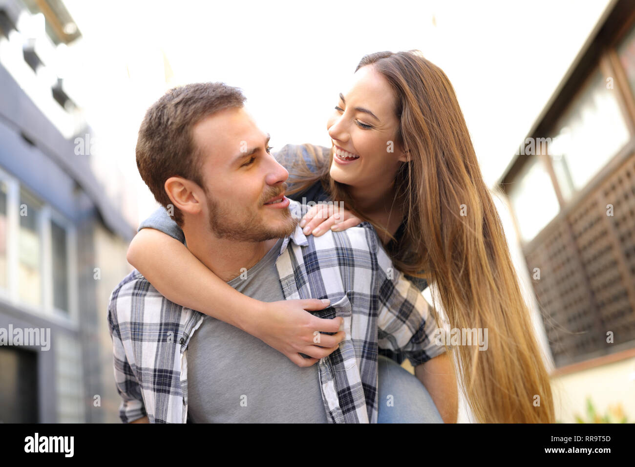 Felice coppia o amici stanno scherzando piggybacking in strada Foto Stock
