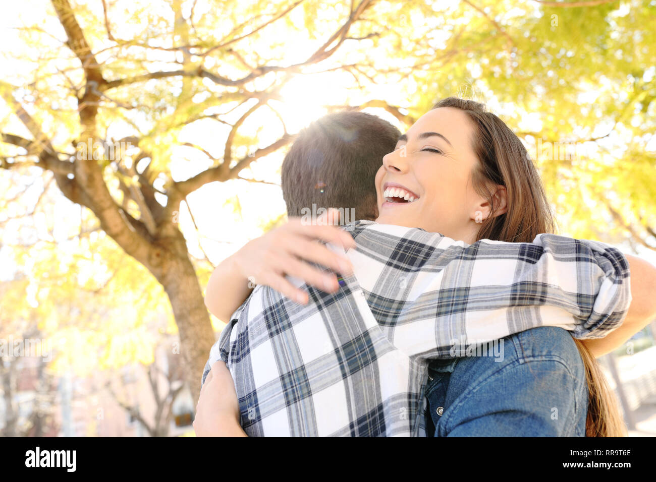 Felice coppia o amici abbracciando in un parco con alberi in background Foto Stock