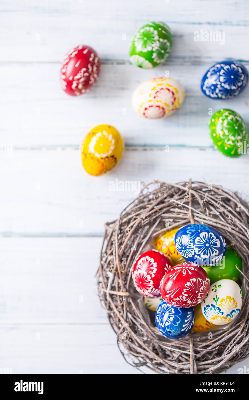 Close-up multicolore di uova di pasqua nel cesto su un tavolo di legno. Foto Stock