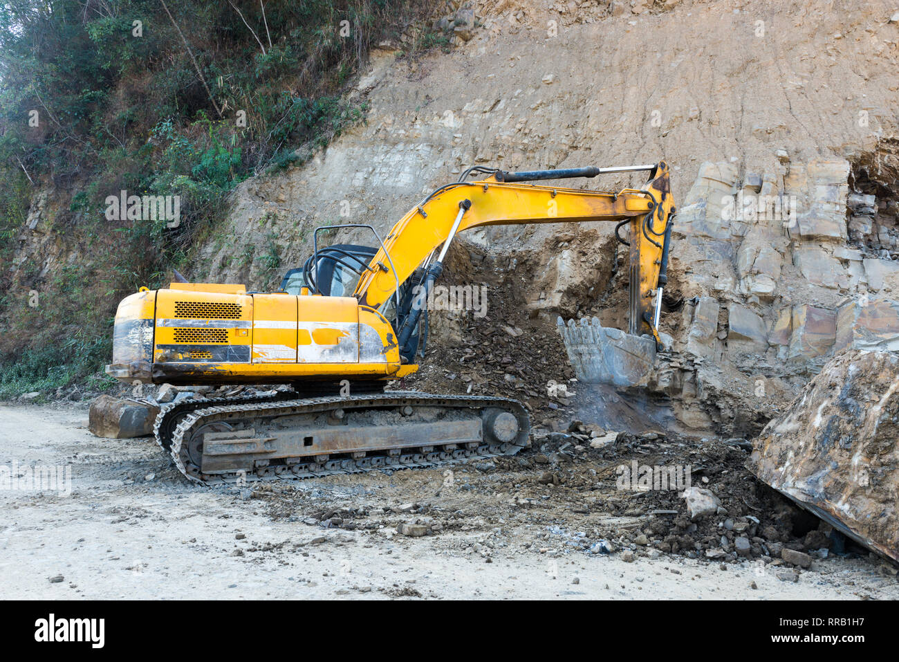 Un escavatore scava e raccoglie il suolo e la pietra per uno slargo progetto Foto Stock