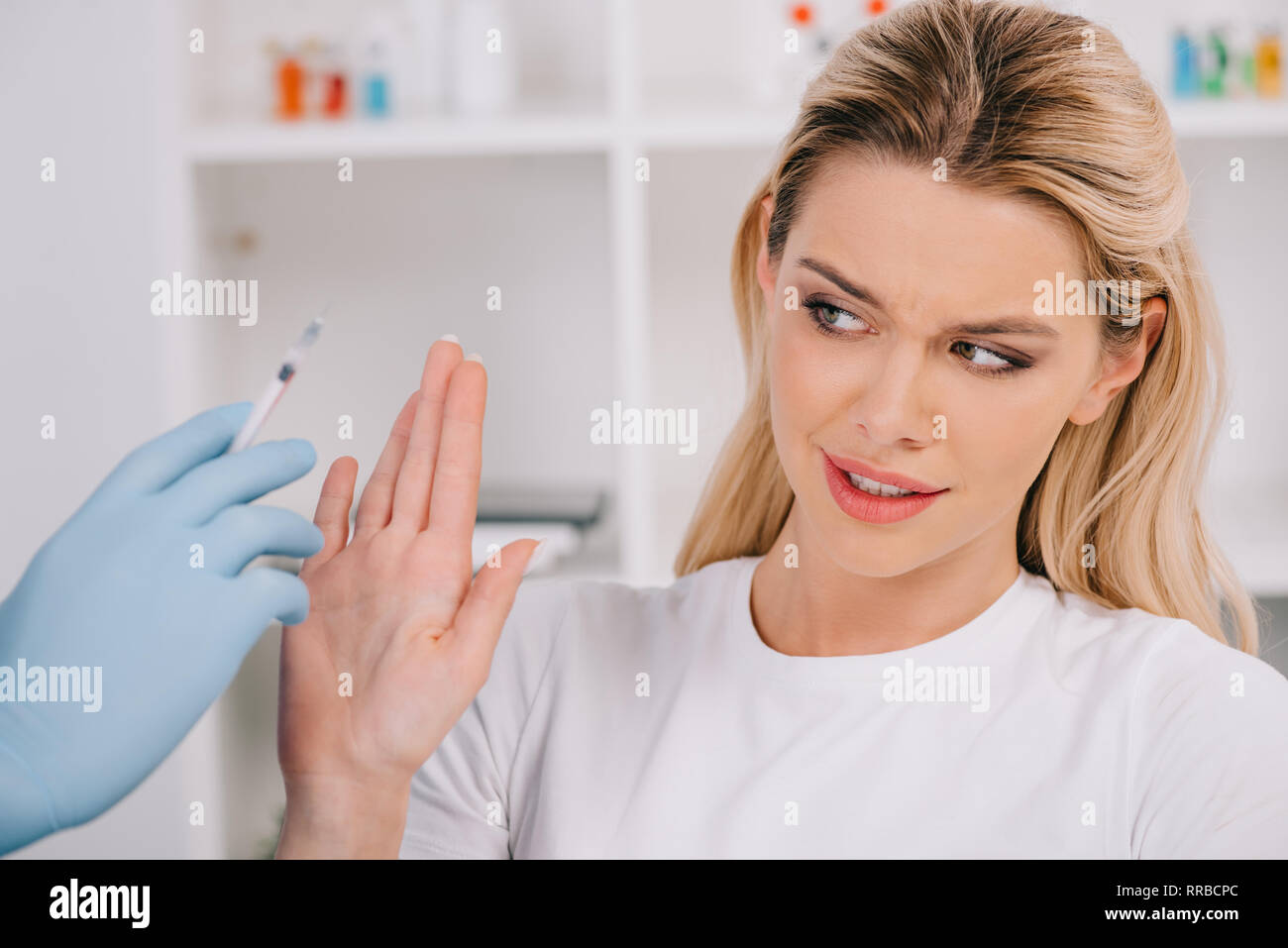 Donna gesticolando con la mano e il rifiuto di dentista con anestesia locale siringa Foto Stock