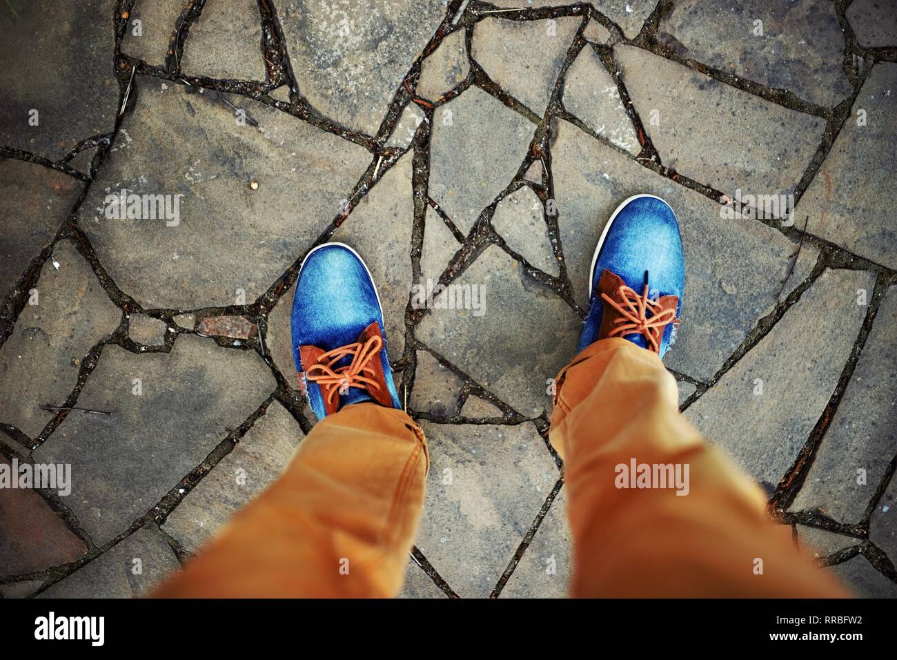Uomini in piedi in jeans e scarpe da ginnastica rusty i jeans sono in piedi su una pietra selvatici piastrelle del pavimento Foto Stock