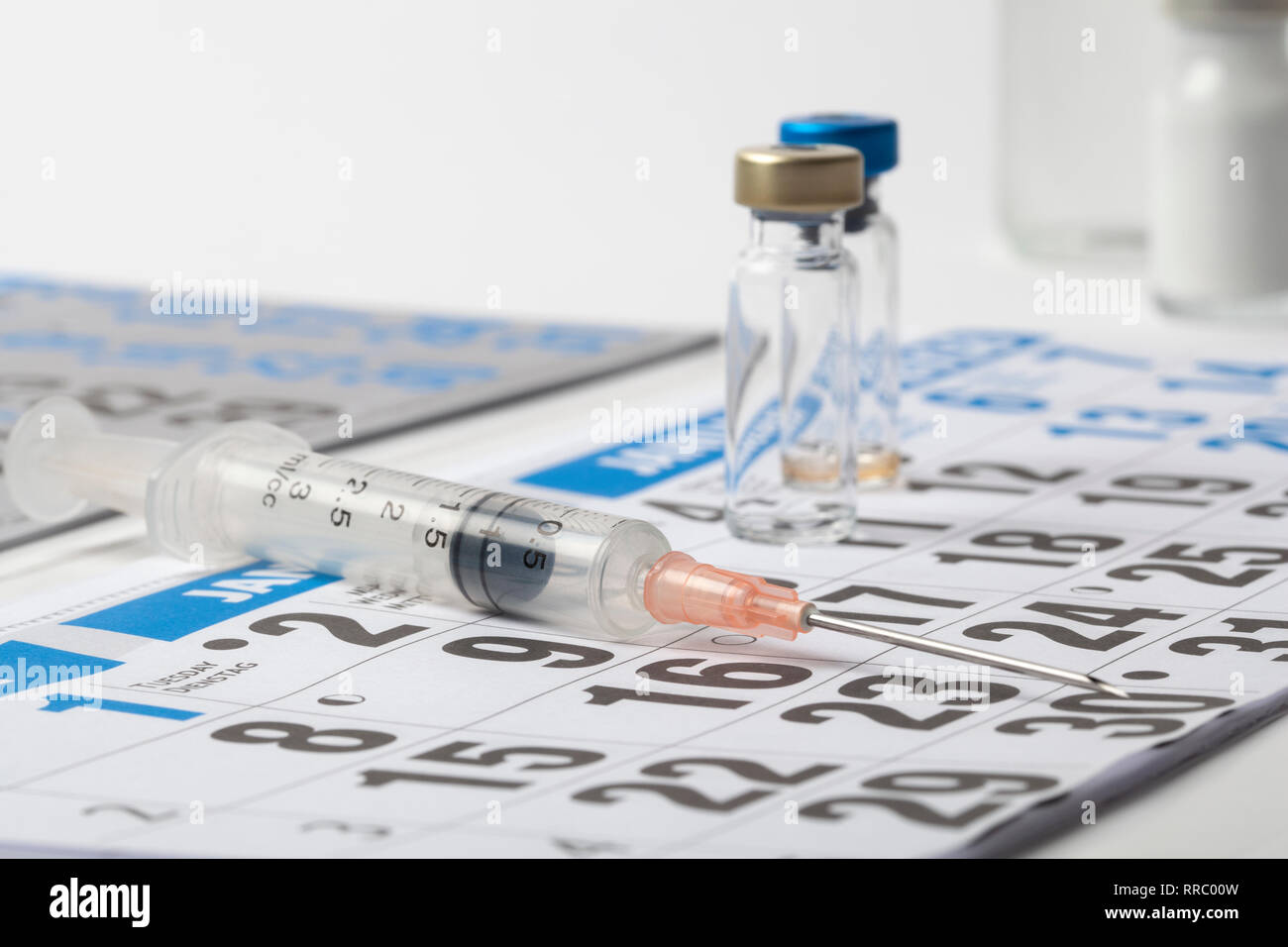 Parecchie fiale trasparenti ampolle di un vaccino e la siringa su un foglio del diario Foto Stock