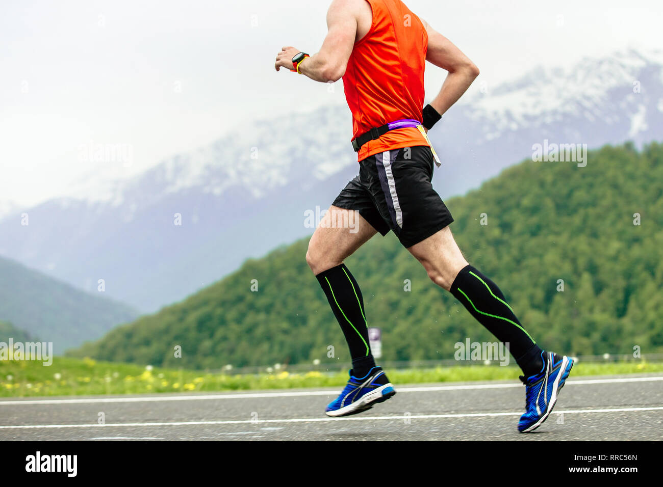 L'uomo runner in calze a compressione in esecuzione su strada in montagna Foto Stock