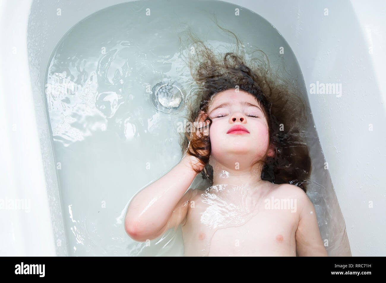 Bambina nuotare nel bagno con gli occhi chiusi. Foto Stock