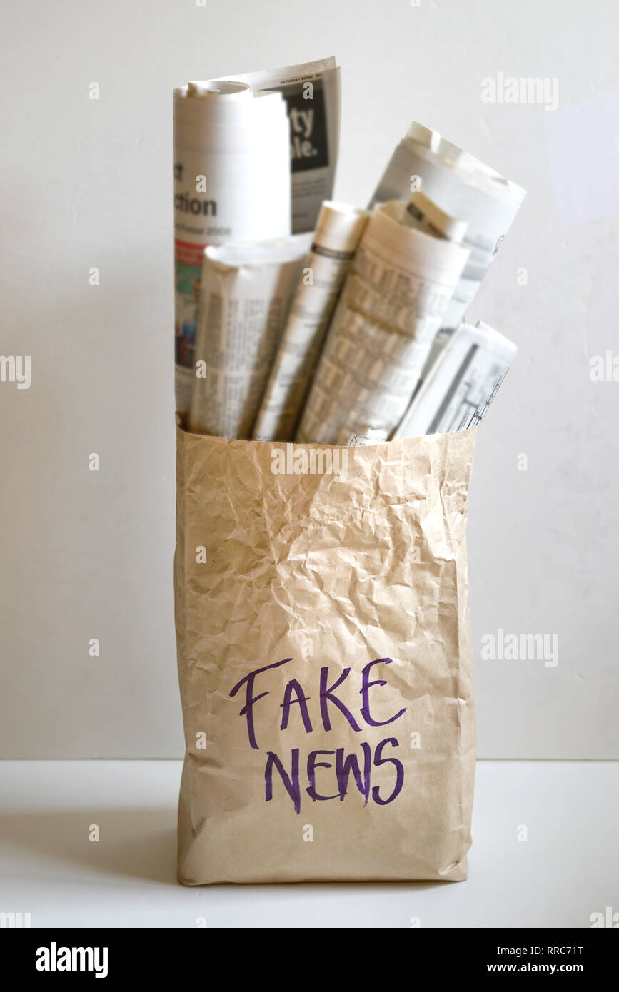 Fake news concetto - la parola "Fake News' sul sacchetto di carta riempito con quotidiani Foto Stock