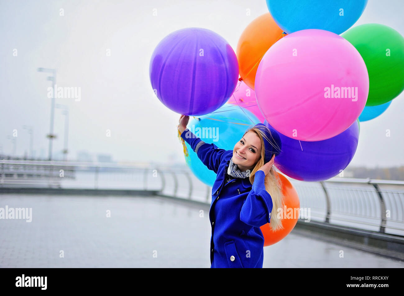 Jumping ragazza con palloncini colorati in mano. Giorno nuvoloso Foto Stock