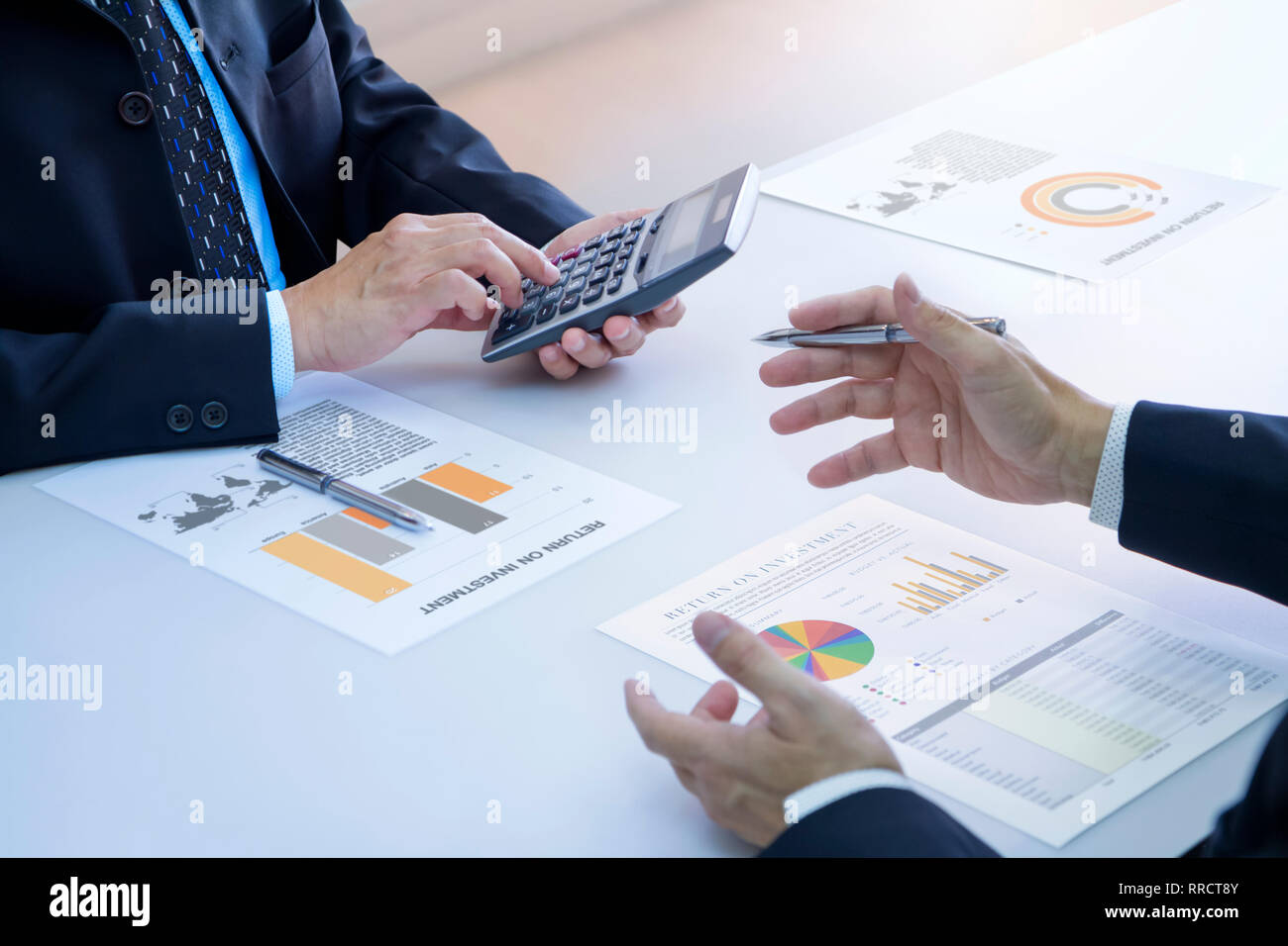 Due imprenditori sono profondamente rivedendo un report finanziari per un ritorno sugli investimenti o rischio di investimento analisi su una scrivania bianca. Inferiore e Superiore destro Foto Stock