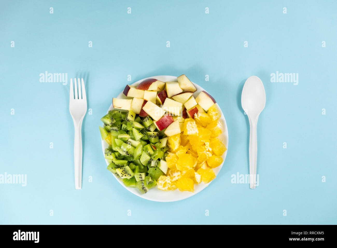 Impianto basato dieta alimentare concetto. Vista superiore della frutta fresca su di una piastra a fondo azzurro con spazio di copia Foto Stock