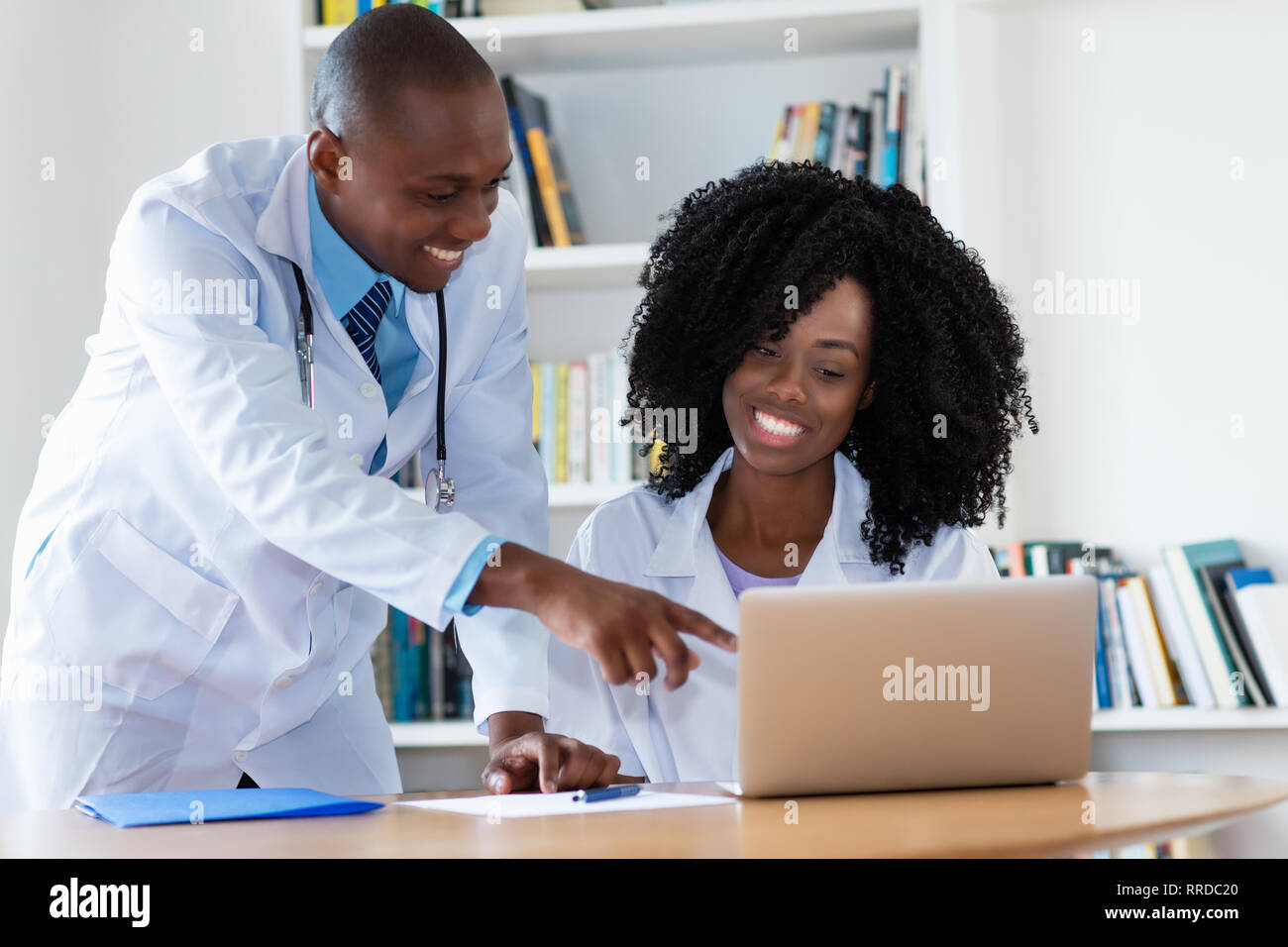 Ridendo americano africano maschio medico e infermiere lavorando al computer in ospedale Foto Stock