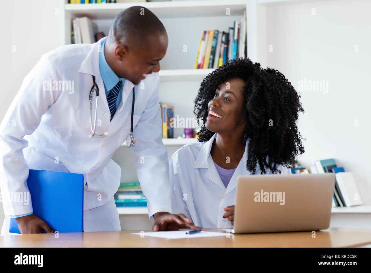 African American medico in capo con giovani donne medico del lavoro all'ospedale Foto Stock