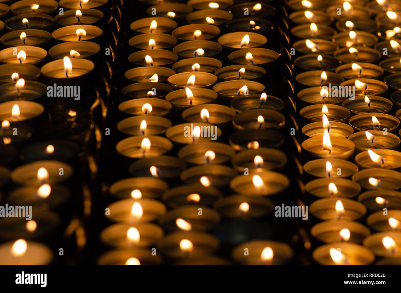 Molte belle candele accese in una fila incandescente con un colore giallo dorato - luce messa a fuoco selettiva Foto Stock