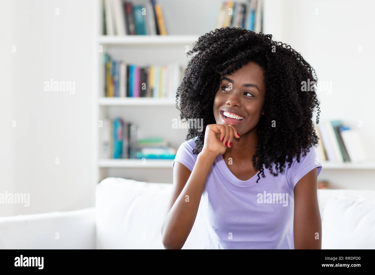 Ridere e sognare americano africano donna al chiuso in casa Foto Stock