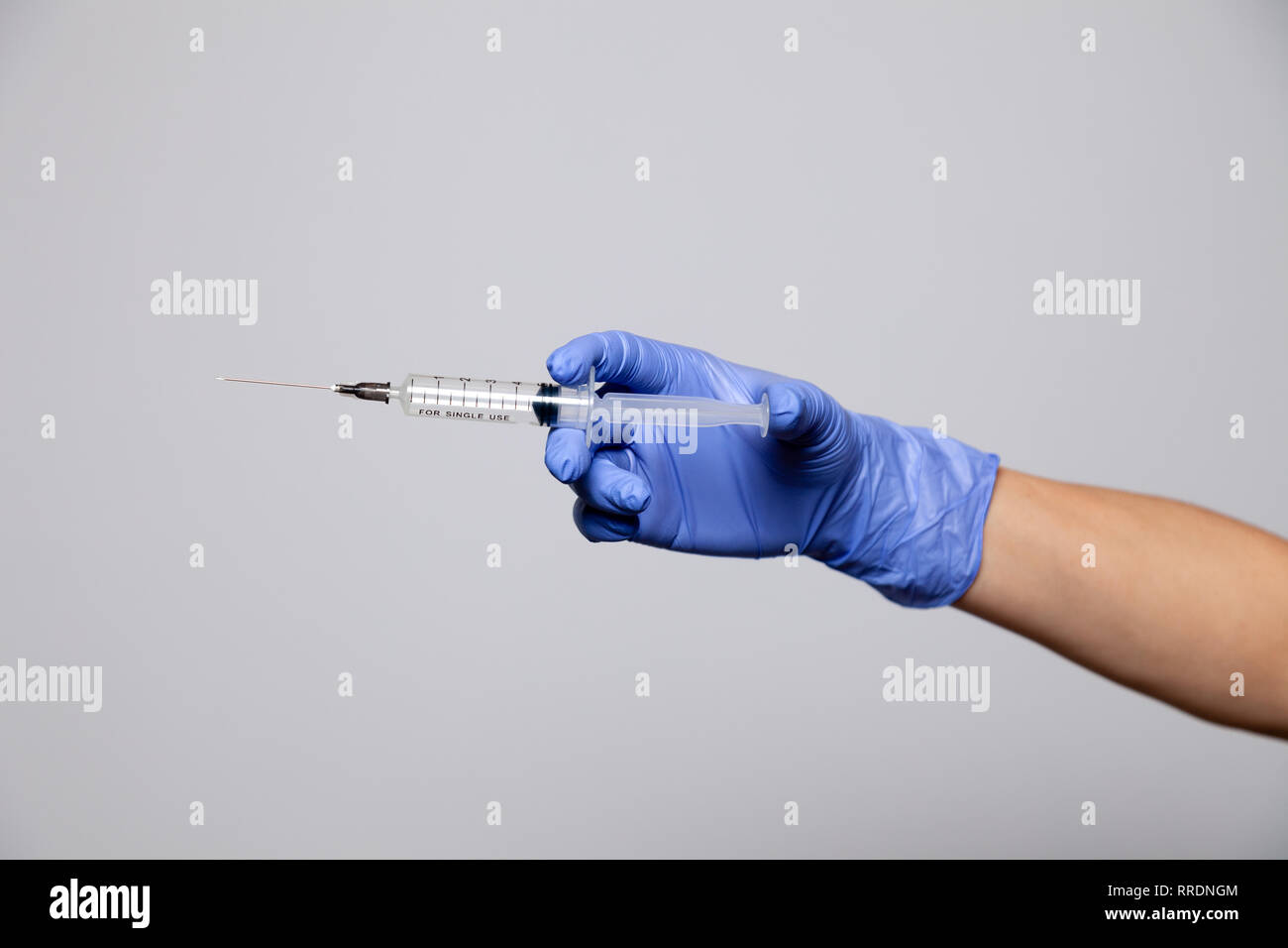 Primo piano medico la mano in gomma guanto Porpora tenendo la siringa trasparente senza tappo. Isolato su sfondo bianco. Nozione di rifiuto di vaccinatio Foto Stock