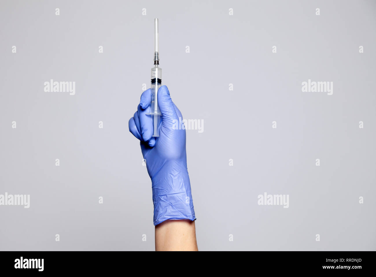 Primo piano medico la mano in gomma guanto Porpora tenendo la siringa trasparente senza tappo. Isolato su sfondo bianco. Nozione di rifiuto di vaccinatio Foto Stock