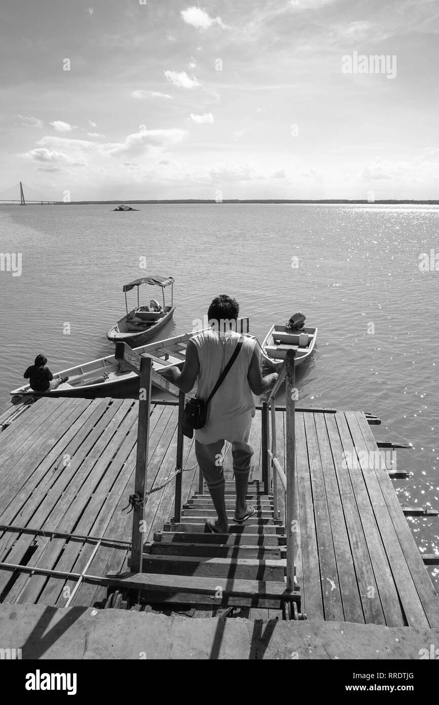 Vista di un uomo che cammina verso il basso il jetty scale e un uomo di legare una corda per fissare la sua barca a un pontile in legno. vista da un pontile in legno Foto Stock