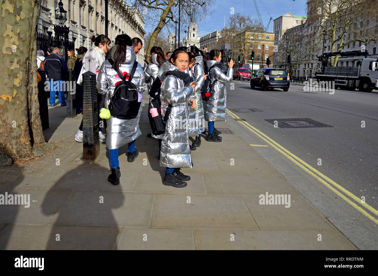Londra, Inghilterra, Regno Unito. Gruppo di visitare gli scolari giapponesi in argento identici cappotti in Whitehall, al di fuori di Downing Street Foto Stock