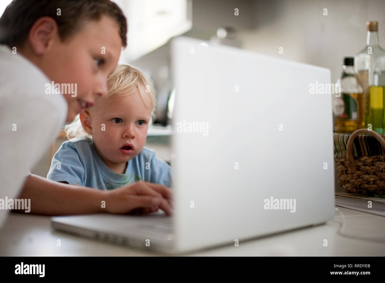 Fratello più anziano che mostra più giovane fratello scioccante di cose su un computer portatile Foto Stock