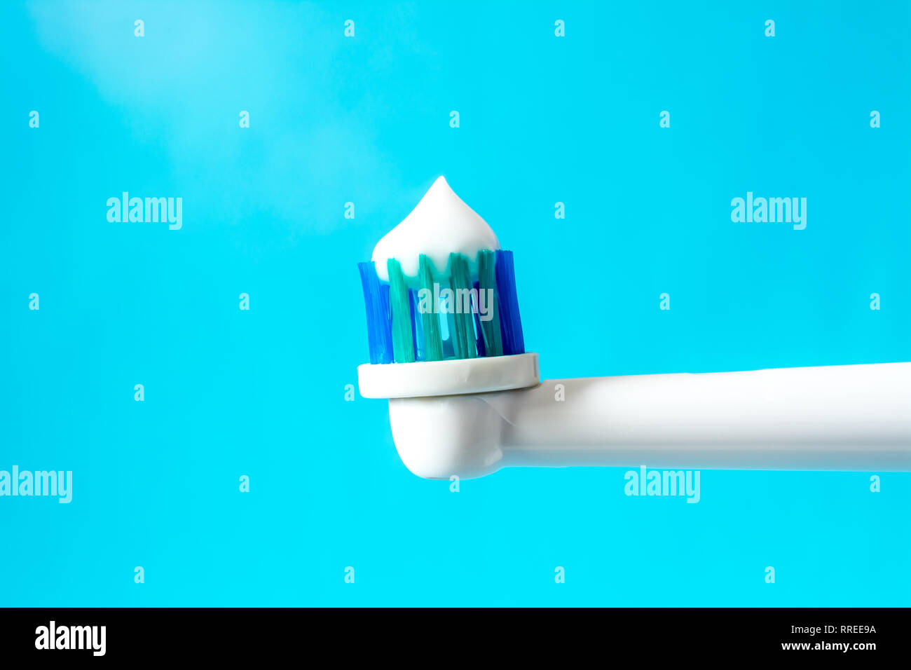 Spazzolino elettrico da denti con dentifricio closeup su uno sfondo blu Foto Stock