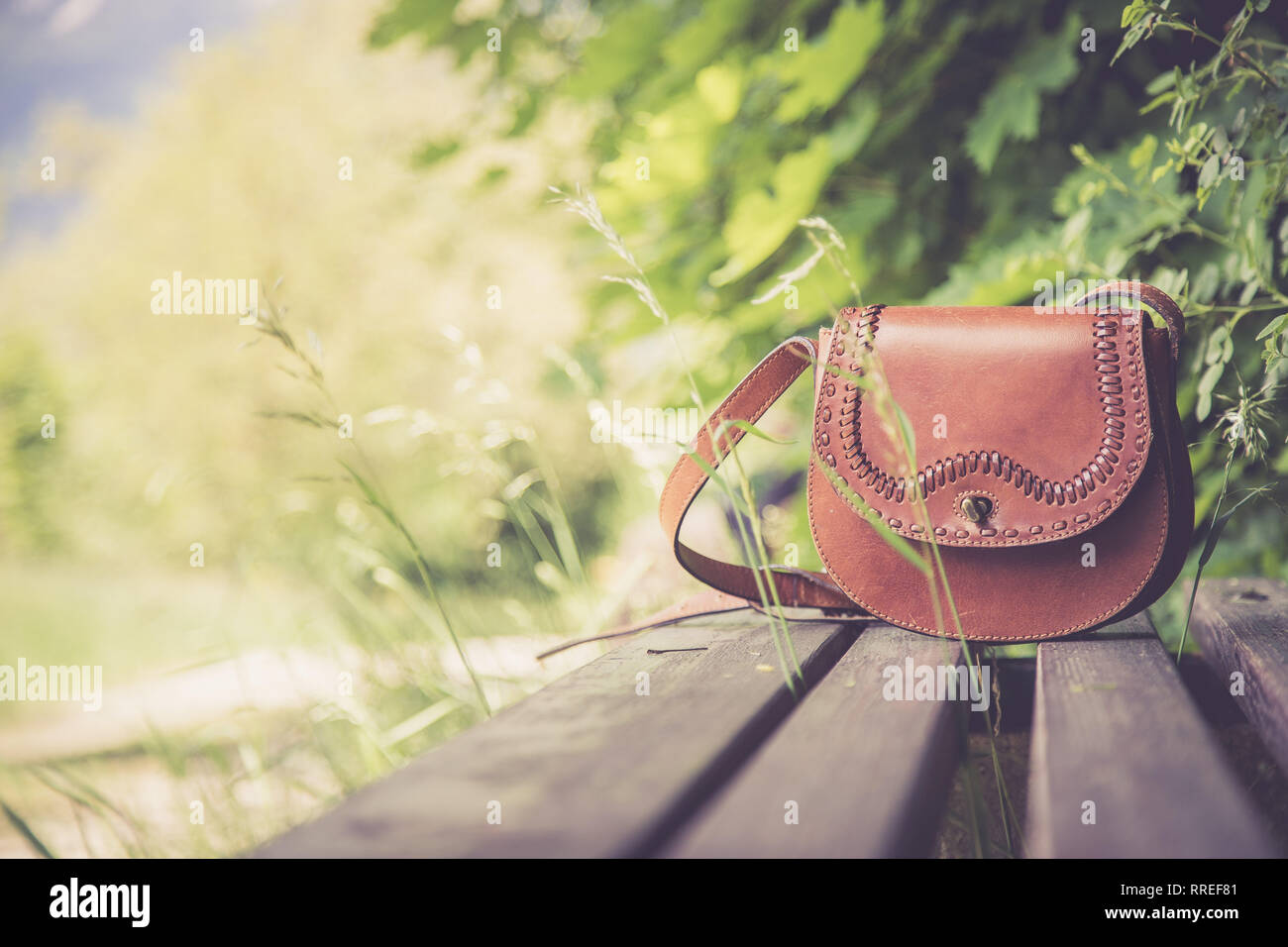 In pelle borsa a mano giace su un parco di legno da banco, estate, nessuno Foto Stock