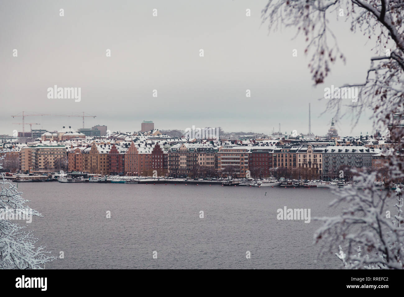 Vecchi edifici di appartamenti dal fiume su di un panno umido giornata invernale con neve e nebbia, Stoccolma Svezia Foto Stock