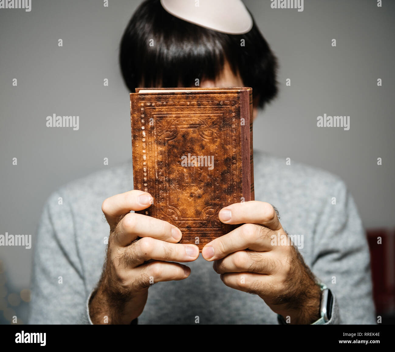 Maschio ebreo indossando kippa , lettura orante bi-lingue ebraico mahzor francese libro di preghiera da 1920 utilizzato in alto i Giorni santi di Rosh Hashanah e Yom Kippur azienda libro di fronte al viso. Foto Stock