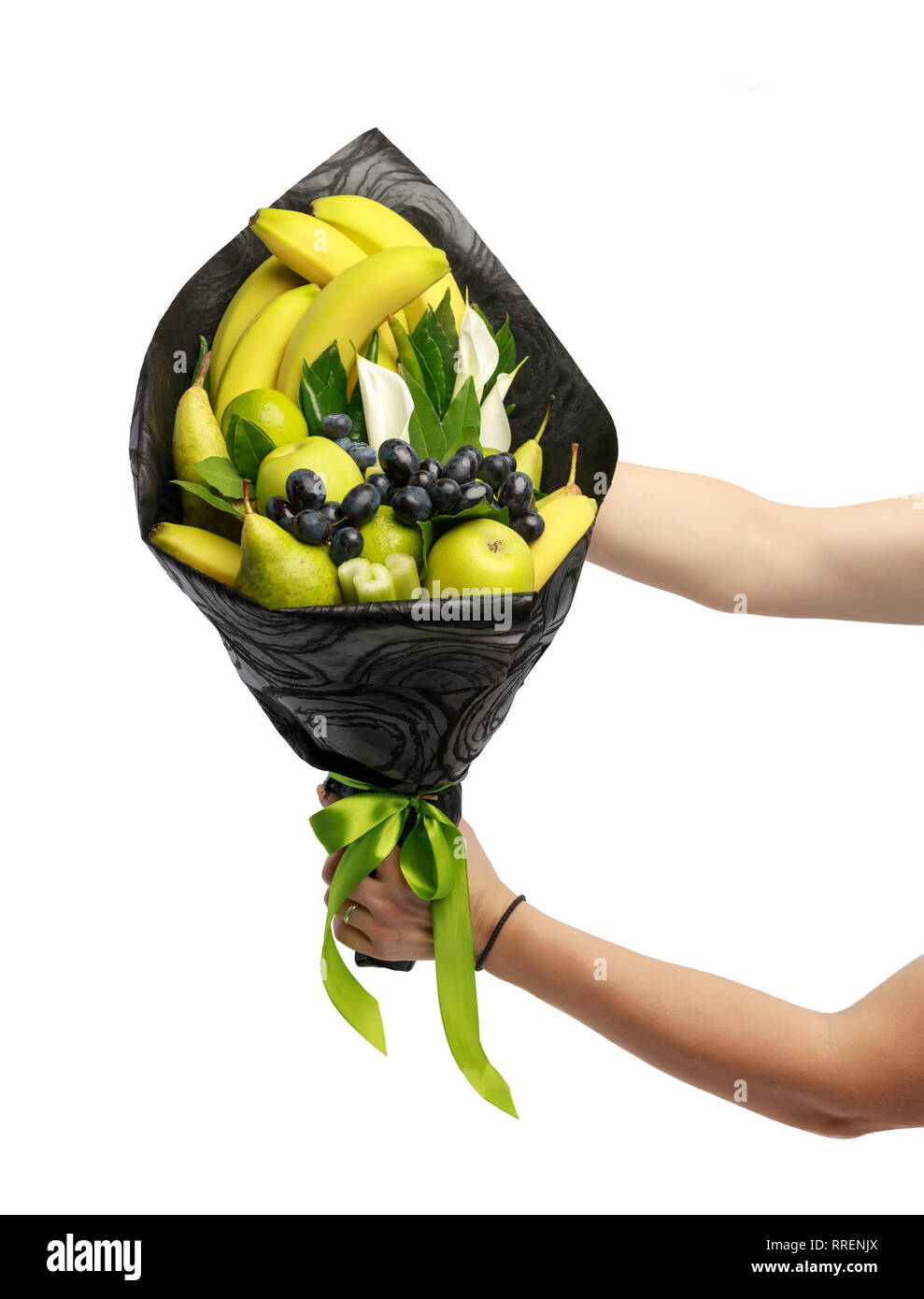 Insolito bouquet commestibile costituito di banane, pere, mele, calce e uve nere nelle mani di una donna su uno sfondo bianco Foto Stock