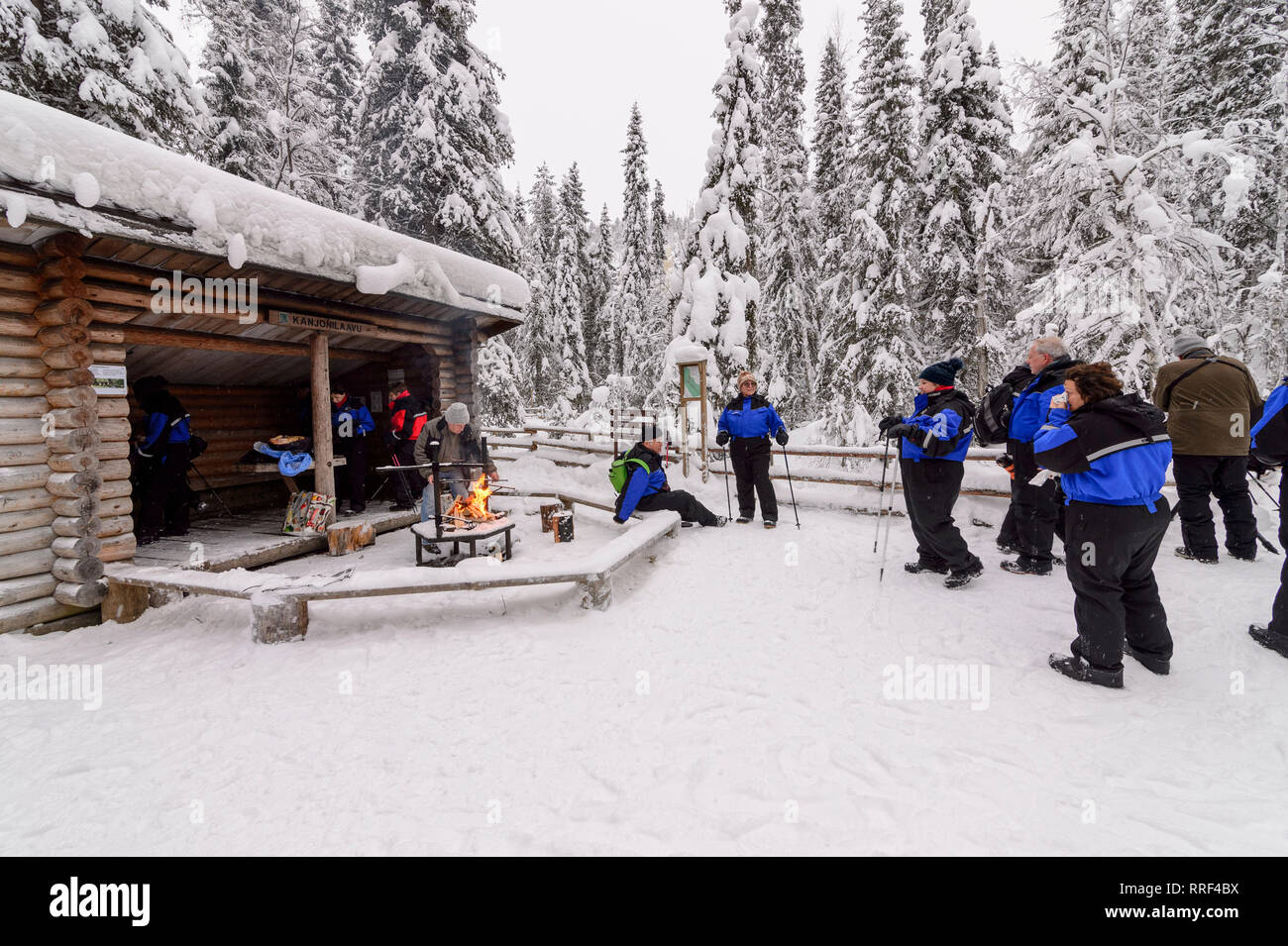 Gruppo di turisti avente una interruzione in corrispondenza di un fuoco di campo sulla neve nel Canyon Korouoma, Finlandia Foto Stock