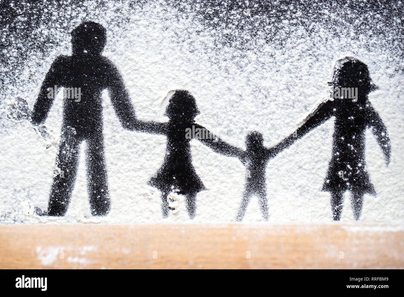 La figura farina nella forma di famiglia cifre su una tavola nera. Per la cottura della pizza. Il concetto di vacanza in famiglia. Foto Stock