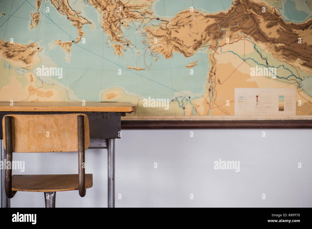 Banchi vuoti in aula scolastica con mappa del mondo. Foto Stock