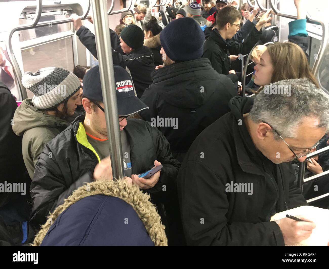 Affollato treno della metropolitana auto piena di gente venuta a casa dal lavoro in un freddo pomeriggio invernale nella Città di New York. Foto Stock