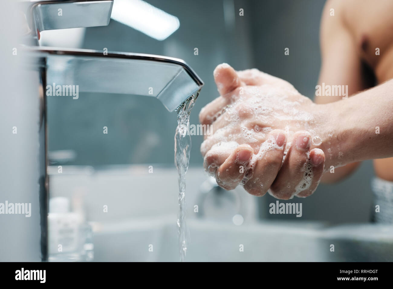L'uomo lavarsi le mani con acqua e sapone nel bagno Foto Stock