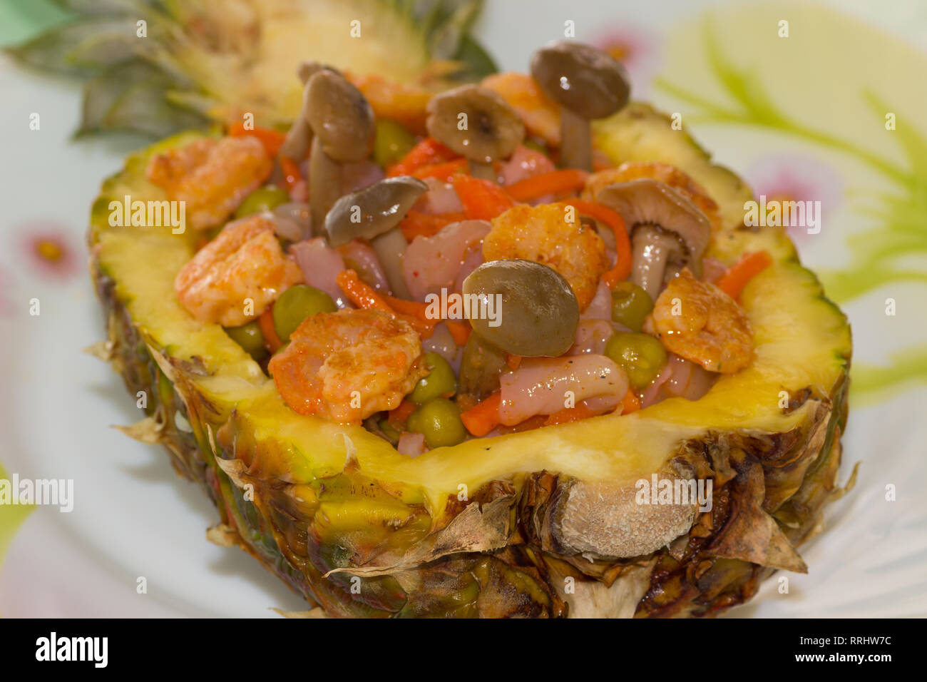 Insalata di gamberetti, calamari, coreano di carote e piselli verdi con funghi nell ananas su una piastra Foto Stock