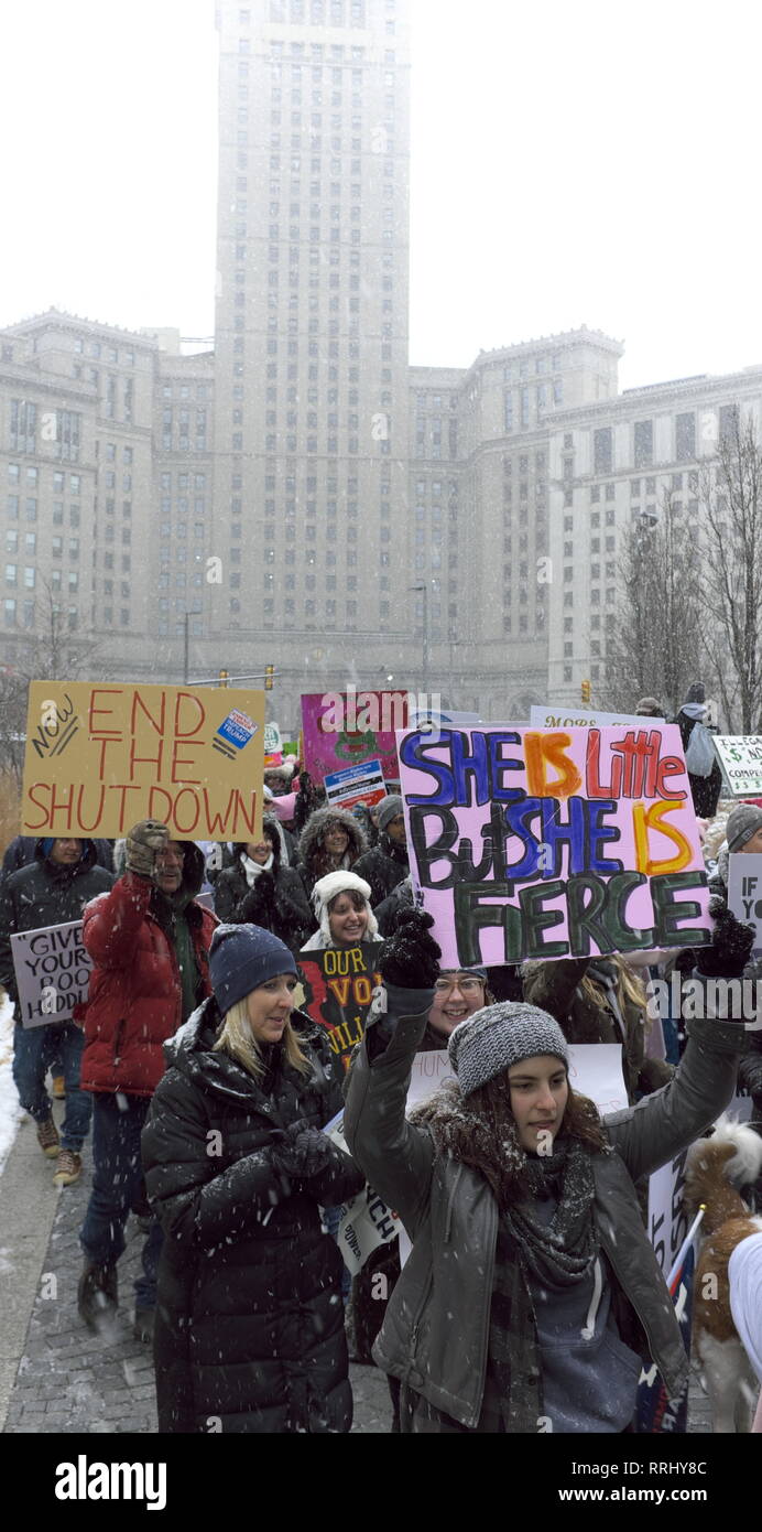 2019 donne partecipanti marzo brave la neve in Cleveland, Ohio, USA come essi marzo attraverso la piazza con il profilarsi Torre del terminale sul retro Foto Stock