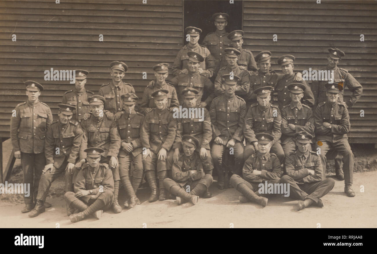 Vintage Cartolina fotografica che mostra un plotone di soldati britannici che pongono al di fuori del loro campo capanna. Foto Stock