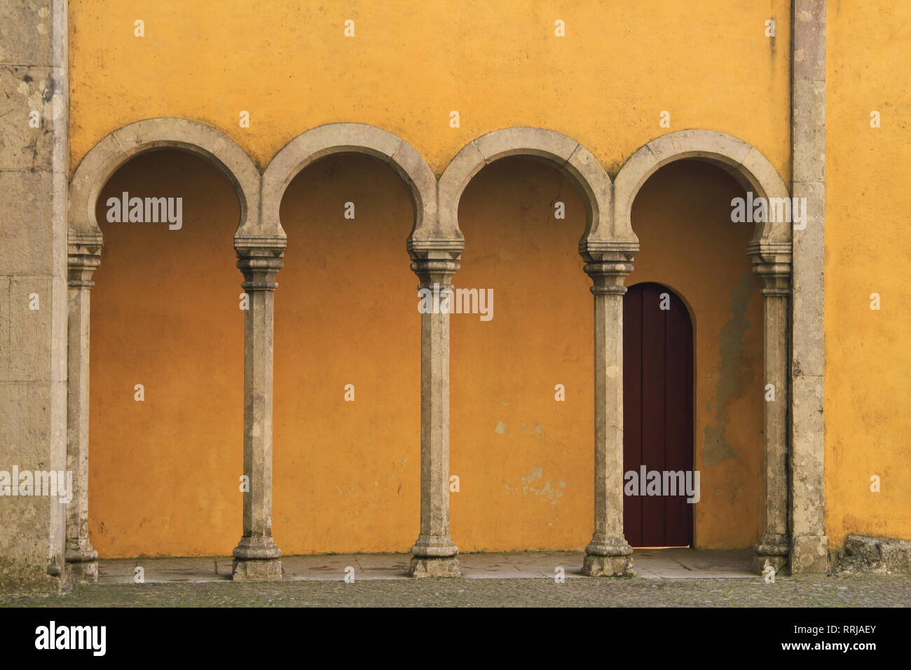 Parete gialla con colonne ed archi, pena Palace, Sintra, Portogallo Foto Stock