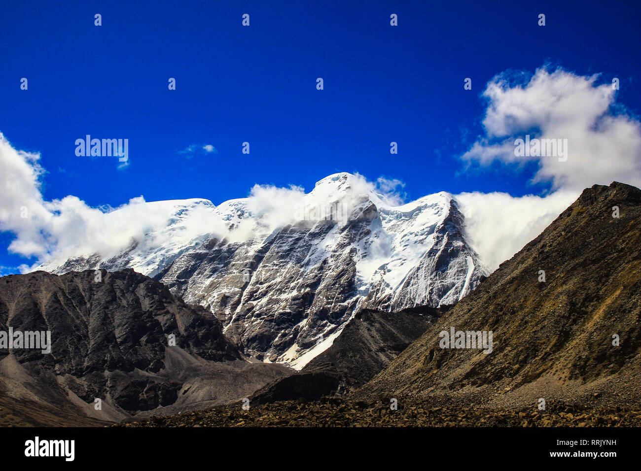 Paesaggio del profondo cielo blu ghiaccio e vette innevate delle montagne himalayane con il bianco delle nuvole durante il giorno Foto Stock