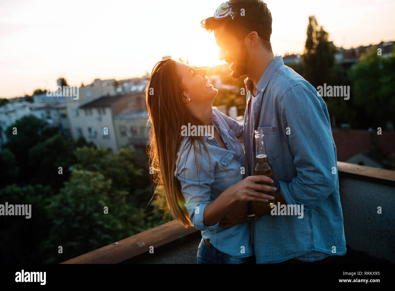 Giovane flirtare mentre si sorseggia un drink sulla terrazza sul tetto Foto Stock