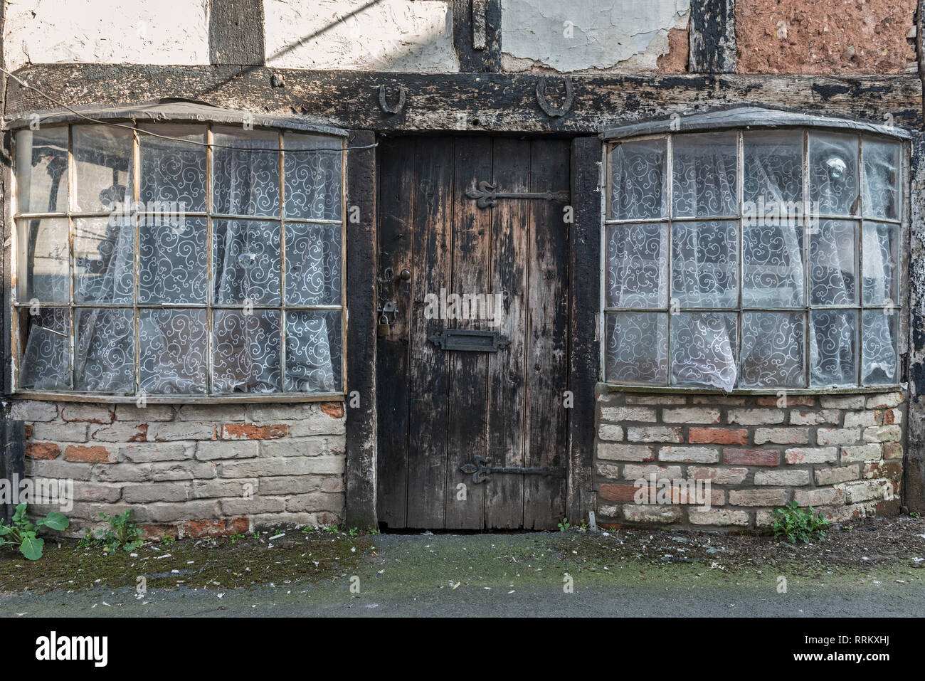 Leominster, Herefordshire, UK. Ferri di cavallo inchiodati al di sopra della porta di un cottage abbandonati con le vecchie finestre di prua, in una strada tranquilla di questa cittadina inglese Foto Stock