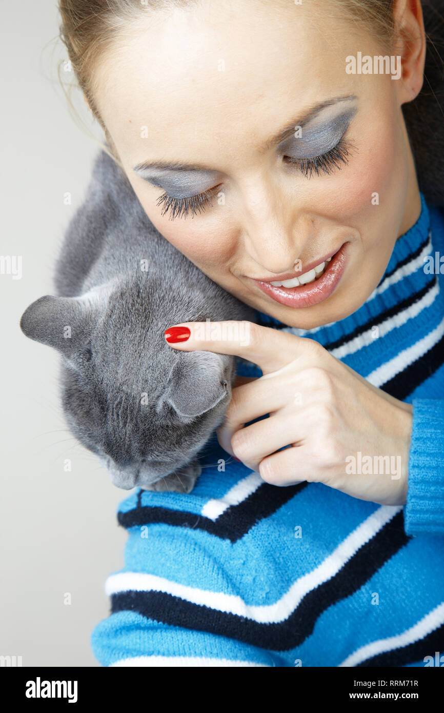 Donna sorridente holding e coccole cat in ambienti interni Foto Stock