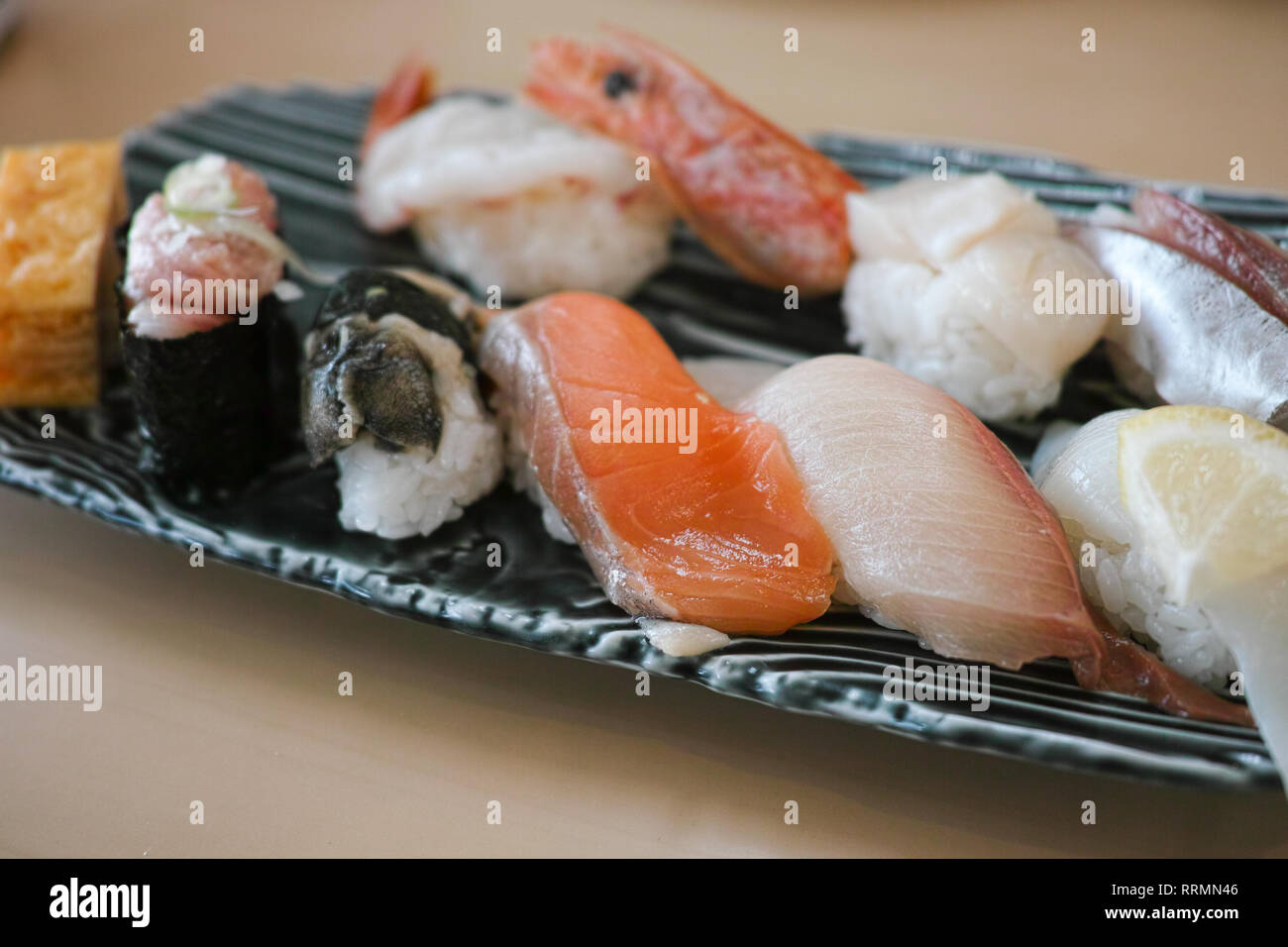 Un assortimento di sushi fresco su una piastra, compresi i salmoni, bonito, gamberetti, tonno, calamari e un uovo fritto. Foto Stock