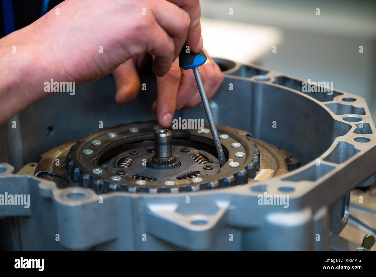 Uomo di riparazione auto di fissaggio parte con un cacciavite. Giovanissimo meccanico presso la sua officina che fissa un auto Foto Stock