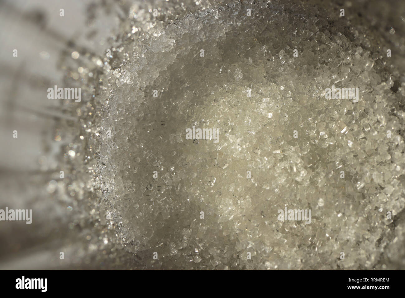 Lo zucchero al fondo di un chiaro vetro sfaccettate. Macro closeup opere d'arte. Foto Stock