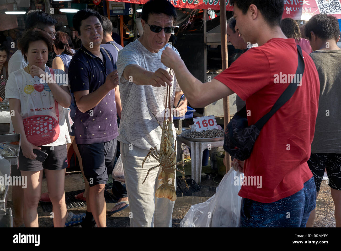 Pesce appena pescato. Acquirente di pesce di aragosta in posa per fotografie con gli amici. Mercato del pesce della Thailandia, Asia sudorientale. Foto Stock