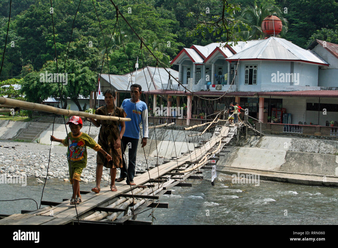 Asse di legno ponte per attraversare il fiume Bahorok a Bukit Lawang, nel nord di Sumatra, Indonesia Foto Stock
