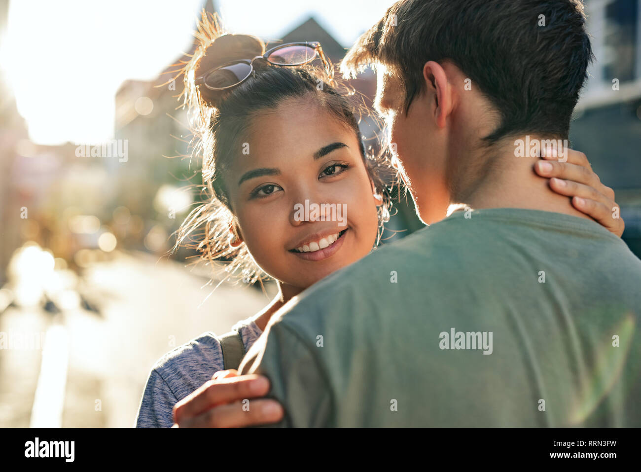 Sorridente giovane donna che abbraccia il suo ragazzo su una strada di città Foto Stock