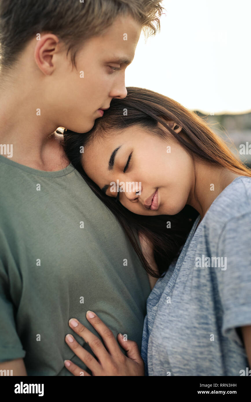 Affettuosa giovane donna che abbraccia il suo ragazzo da un porto Foto Stock