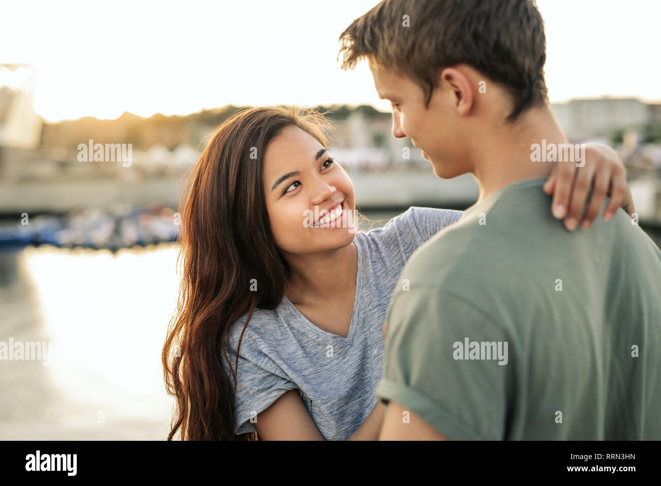 Affettuosa giovane coppia sorridente rimanendo fuori da un porto Foto Stock